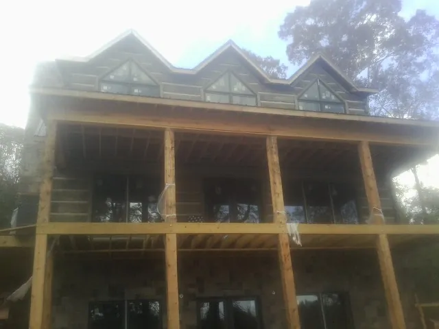 Dormers and porch framing on a large log home under construction — Roof Coating work by our crew in Las Cruces