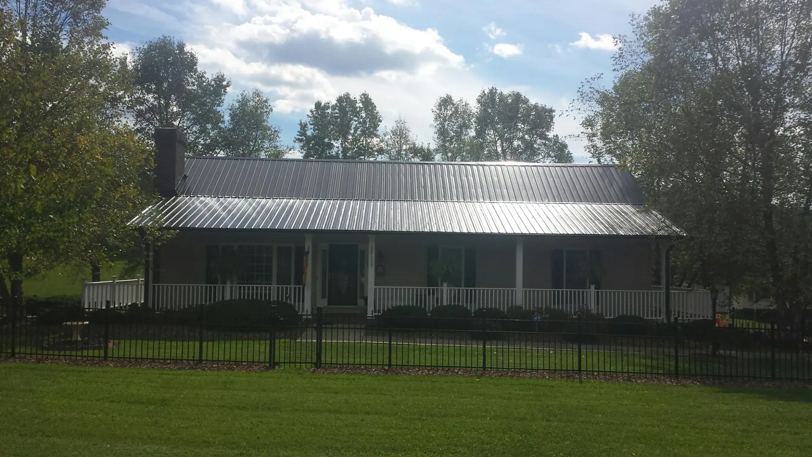 Gray metal roof on a brick ranch with a full width front porch — Gutter Guard Installation work by our crew in Las Cruces