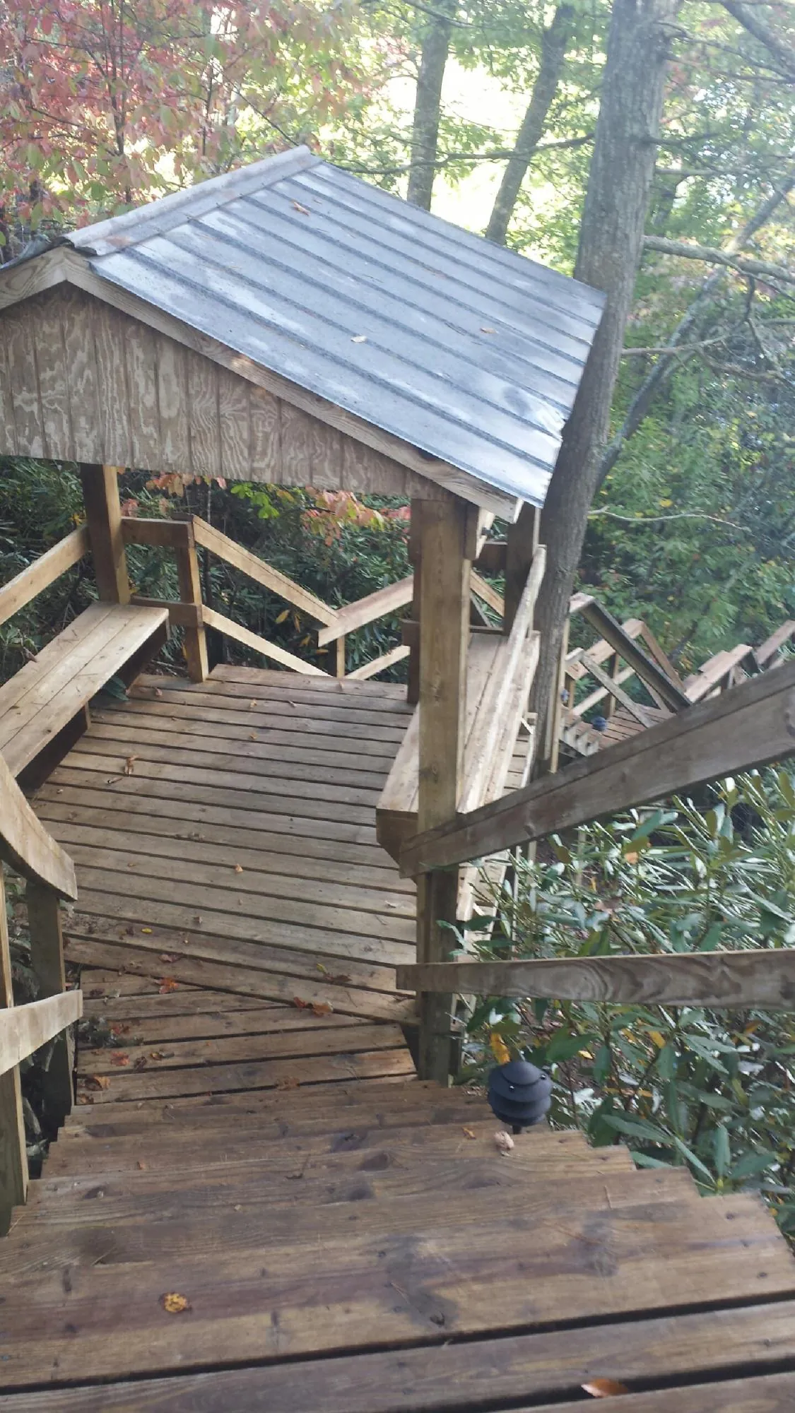 Metal roofed shelter over wooden steps on a wooded walkway — Skylight Repair & Installation work by our crew in Las Cruces