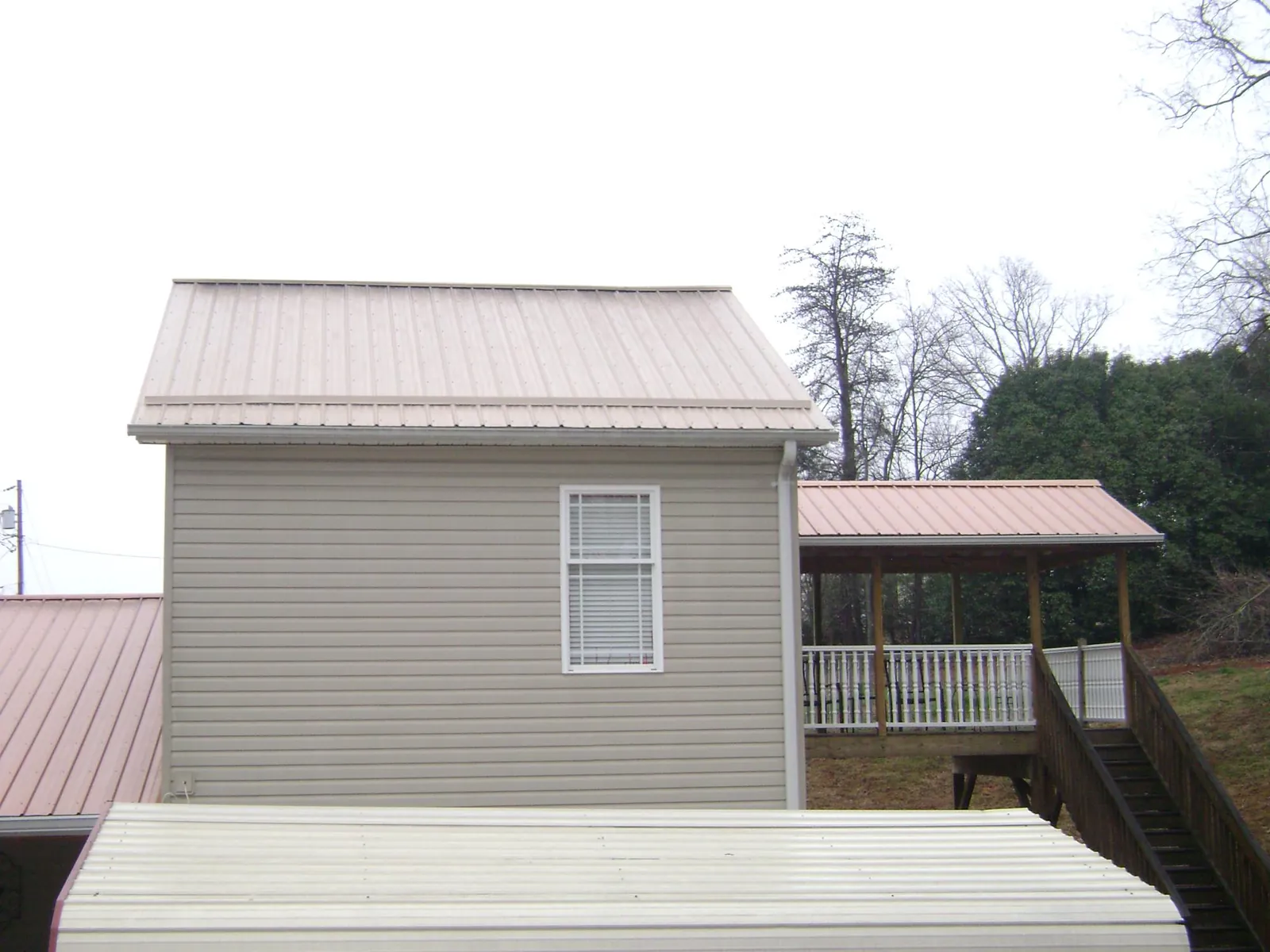 Tan metal roofs on a two story addition and attached porch, from a Roof Replacement job in Las Cruces