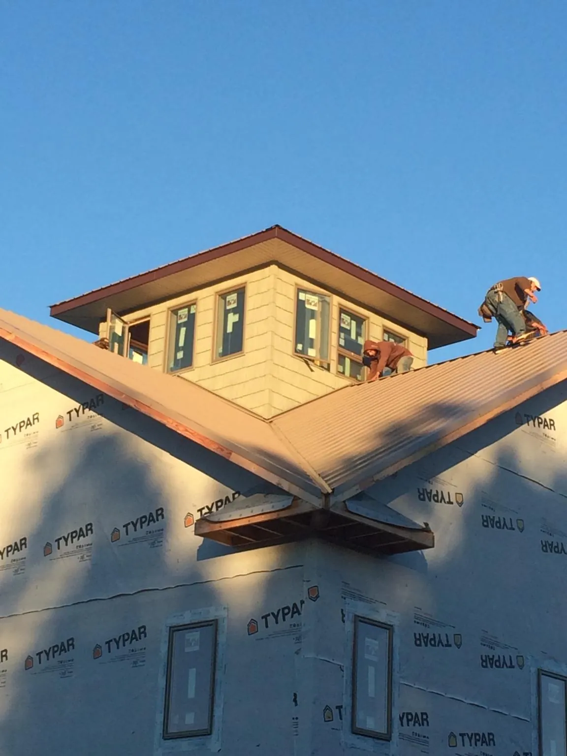 Roofers working around a rooftop cupola on a new metal roof at sunset — Roof Waterproofing in Las Cruces by Roofing Brothers